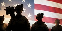 Service members silhouetted against an American flag.